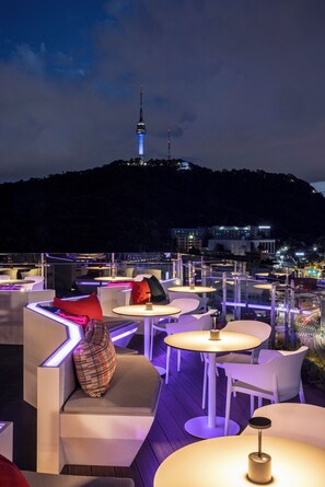 An outdoor seating area with modern tables and chairs, a view of a cityscape and a tower in the background. - ibis Styles Ambassador Seoul Myeongdong (Seoul)