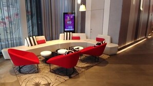 Un espace détente moderne avec un canapé incurvé, des fauteuils rouges et une petite table.