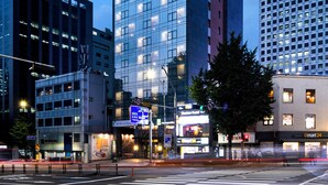 Un hôtel de grande hauteur, doté d’une façade moderne en verre, de nombreux étages et d’une enseigne bien visible au sommet.