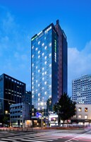 A high-rise hotel with a modern glass facade, multiple floors, and a prominent signage at the top.