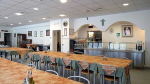 A dining area with multiple tables and chairs, a buffet counter, and a clock on the wall. - Opera Don Calabria Casa per Ferie (Rome)