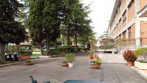A courtyard with a table and chairs, surrounded by potted plants and trees. - Opera Don Calabria Casa per Ferie (Rome)