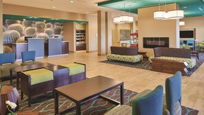 A hotel lobby with seating areas, a reception desk, and a television. - La Quinta Inn & Suites by Wyndham Carlsbad (Carlsbad)