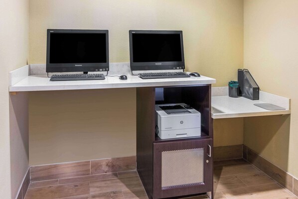 Un espace de travail équipé de deux écrans, d’une imprimante et d’un clavier, le tout posé sur un bureau blanc.