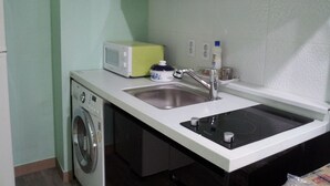 A compact kitchen with a washing machine, a microwave, a sink, and a stove. - Mk Liberty House (Seoul)