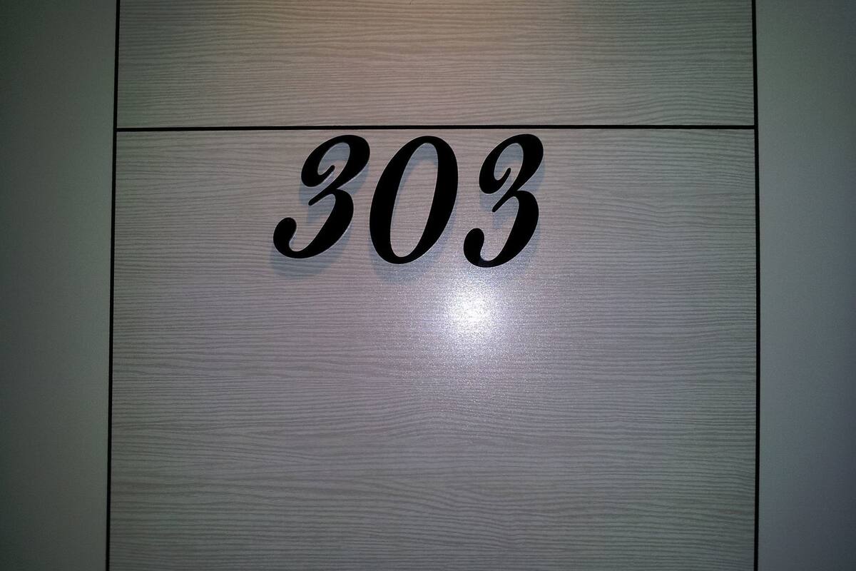 Un cartel con el número 303 en una pared de madera.