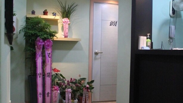A hallway with a reception desk, a door labeled "201", and potted plants. - Mk Liberty House (Seoul)
