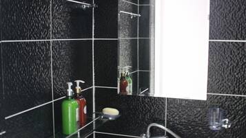 A bathroom with black tiled walls, a white sink, and a mirror.