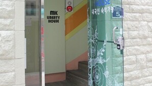 The entrance to MK Liberty House Korea with a glass door, a visible 'GUEST HOUSE' sign, and a 'VISA' sign on the floor. - Mk Liberty House (Seoul)