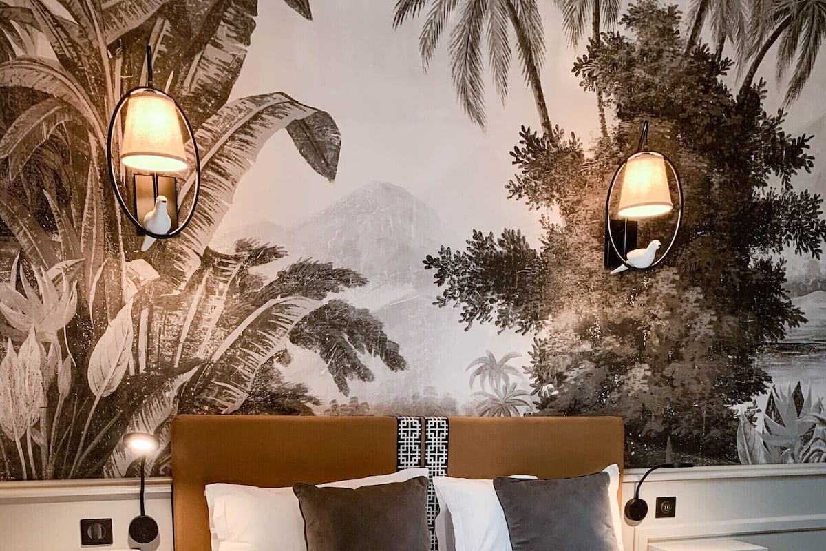 A bedroom with a bed, two nightstands, a headboard, and wall-mounted lamps.