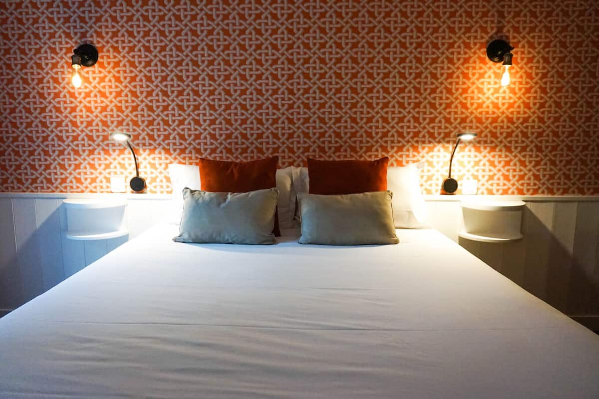 A hotel room with a large bed, two bedside tables, and two wall-mounted lamps.
