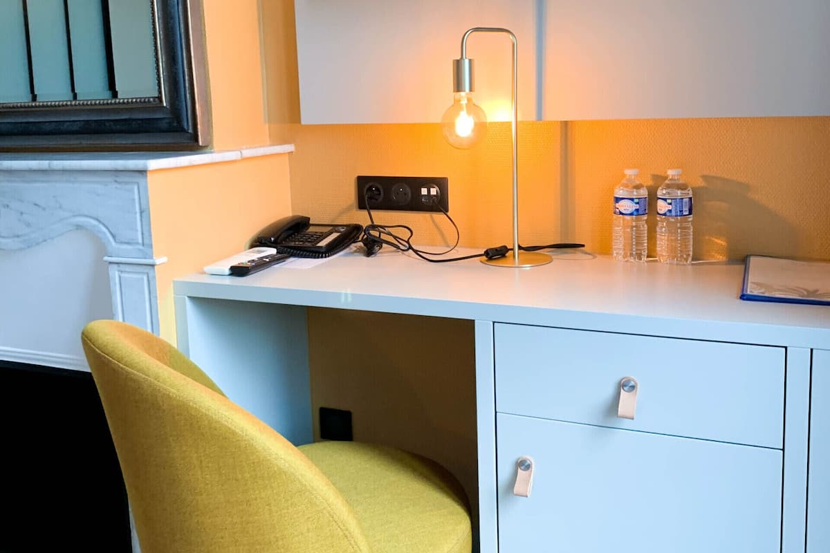 A modern office desk with a lamp, a phone, and water bottles.