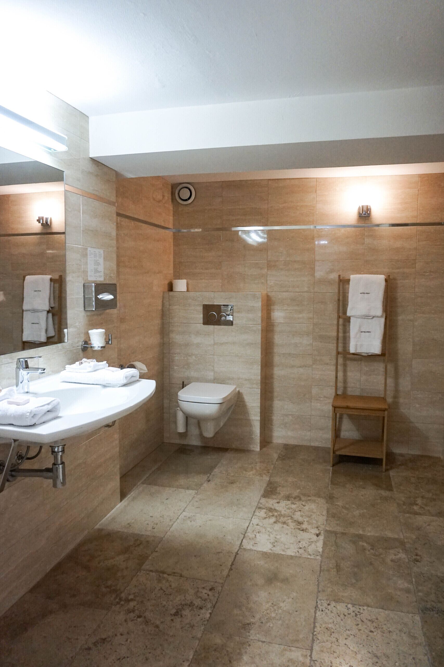 Een moderne badkamer met een wastafel, toilet en handdoekhouder.