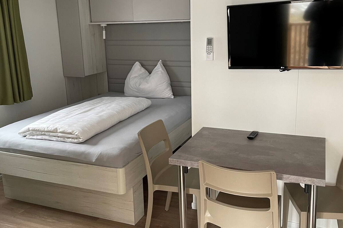 Une chambre d’hôtel de taille réduite, comprenant un lit, un bureau et un téléviseur.