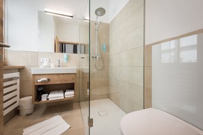 A modern bathroom with a glass-enclosed shower, a white sink, and a toilet.