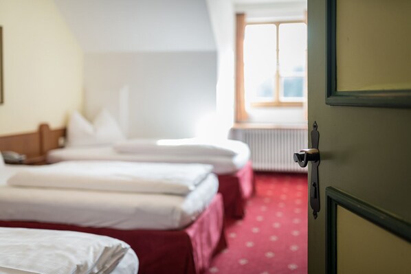 A hotel room with two beds, a red carpet, and a window with a view. - Hotel Plankenhof B&B (Pill)