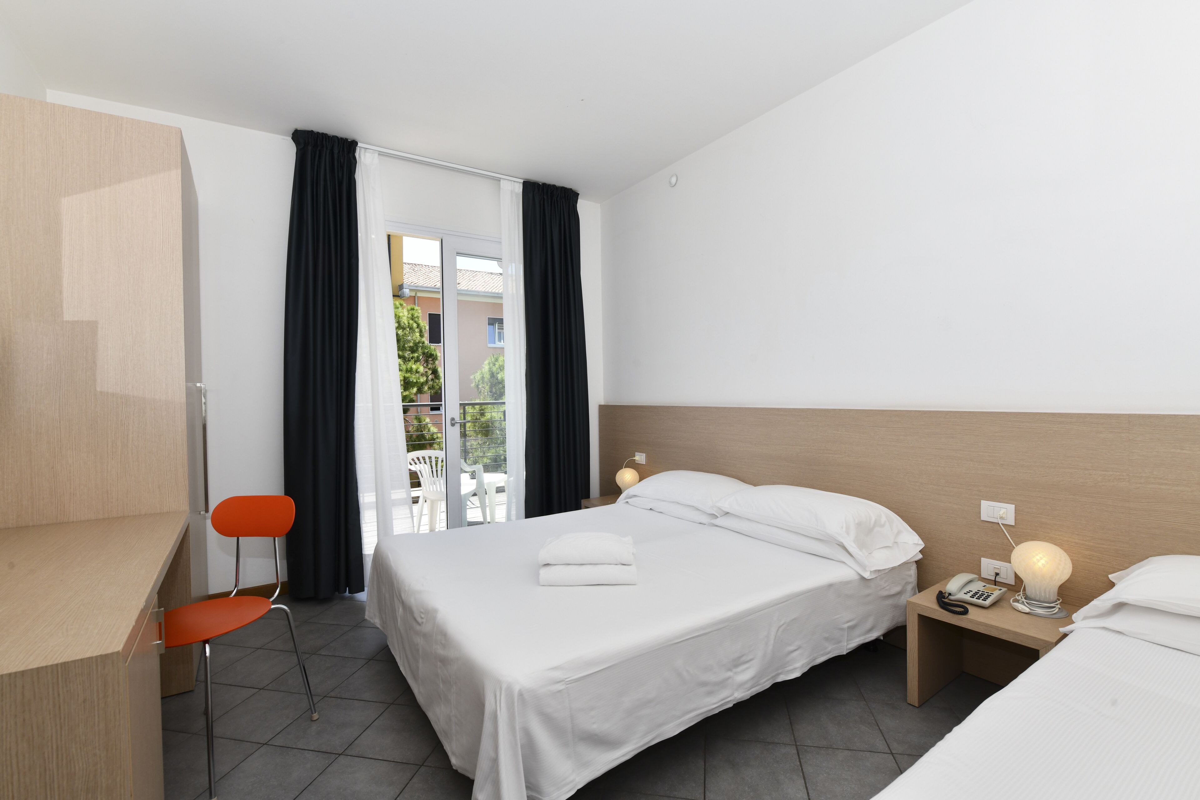 Ein Hotelzimmer mit einem Bett, einem Schreibtisch, einem Stuhl und einem Nachttisch mit Telefon.
