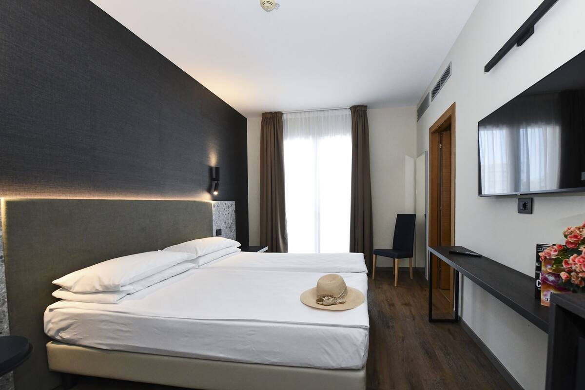 Una camera d'hotel con un letto grande, una TV, una scrivania e una sedia.
