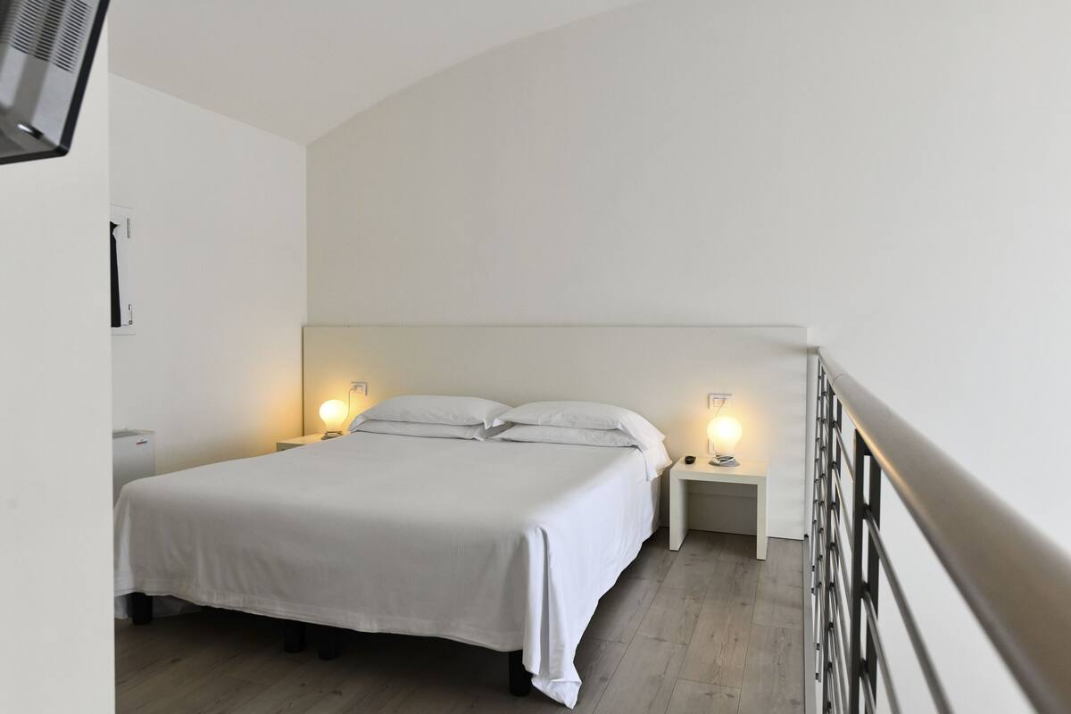 Una camera da letto con un letto, due comodini e un tavolino di fianco al letto.