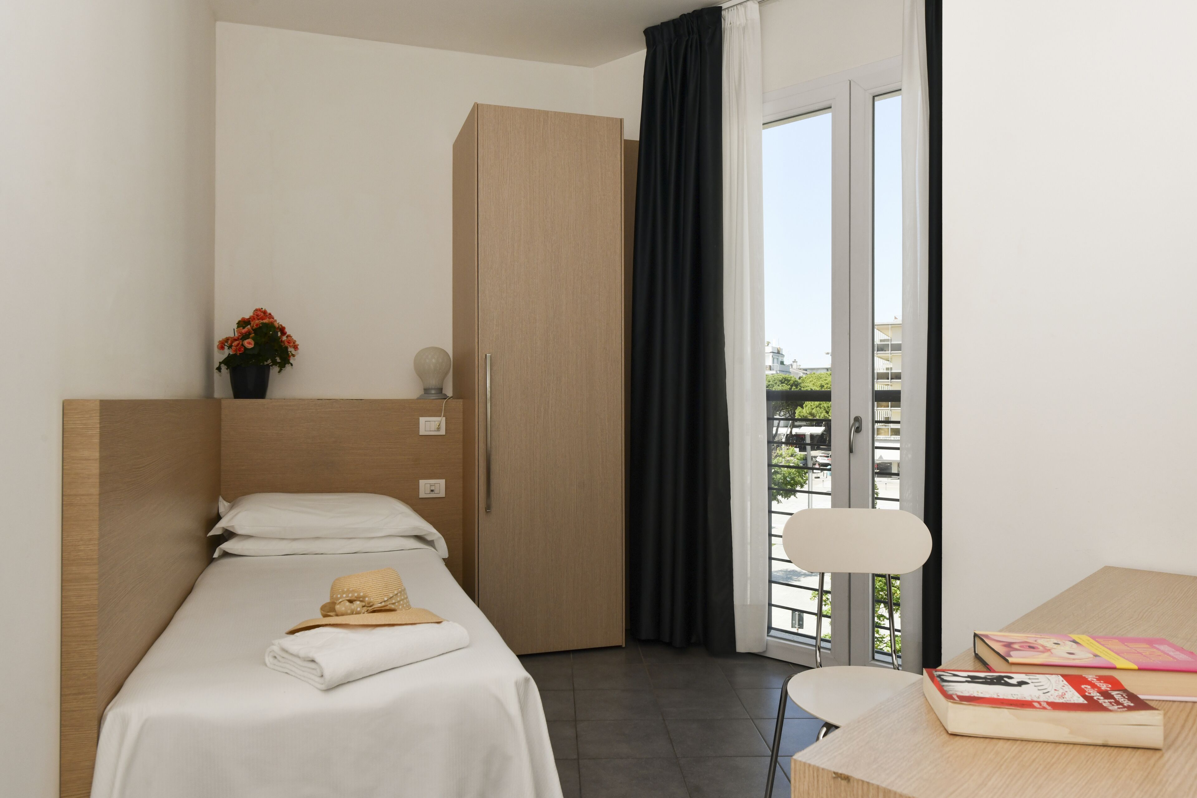 Una habitación de hotel moderna con cama, escritorio, silla, ventana con vistas y puerta.