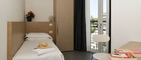 Una habitación de hotel moderna con cama, escritorio, silla, ventana con vistas y puerta.