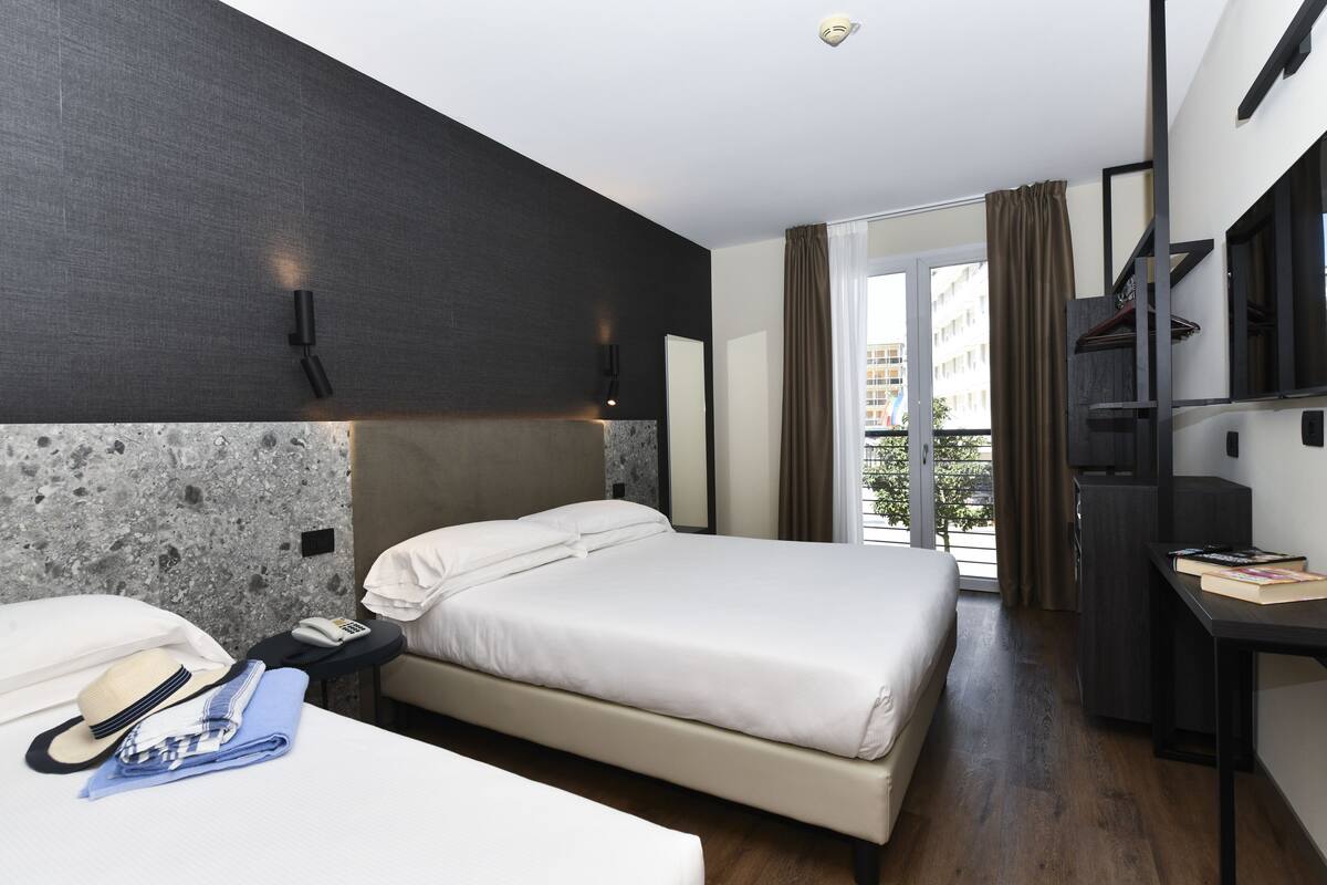 Una moderna camera d'albergo con un letto grande, una scrivania, un telefono e vista sull'esterno.