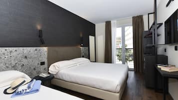 Moderni hotellihuone, jossa on suuri sänky, työpöytä, puhelin ja näkymä ulos.