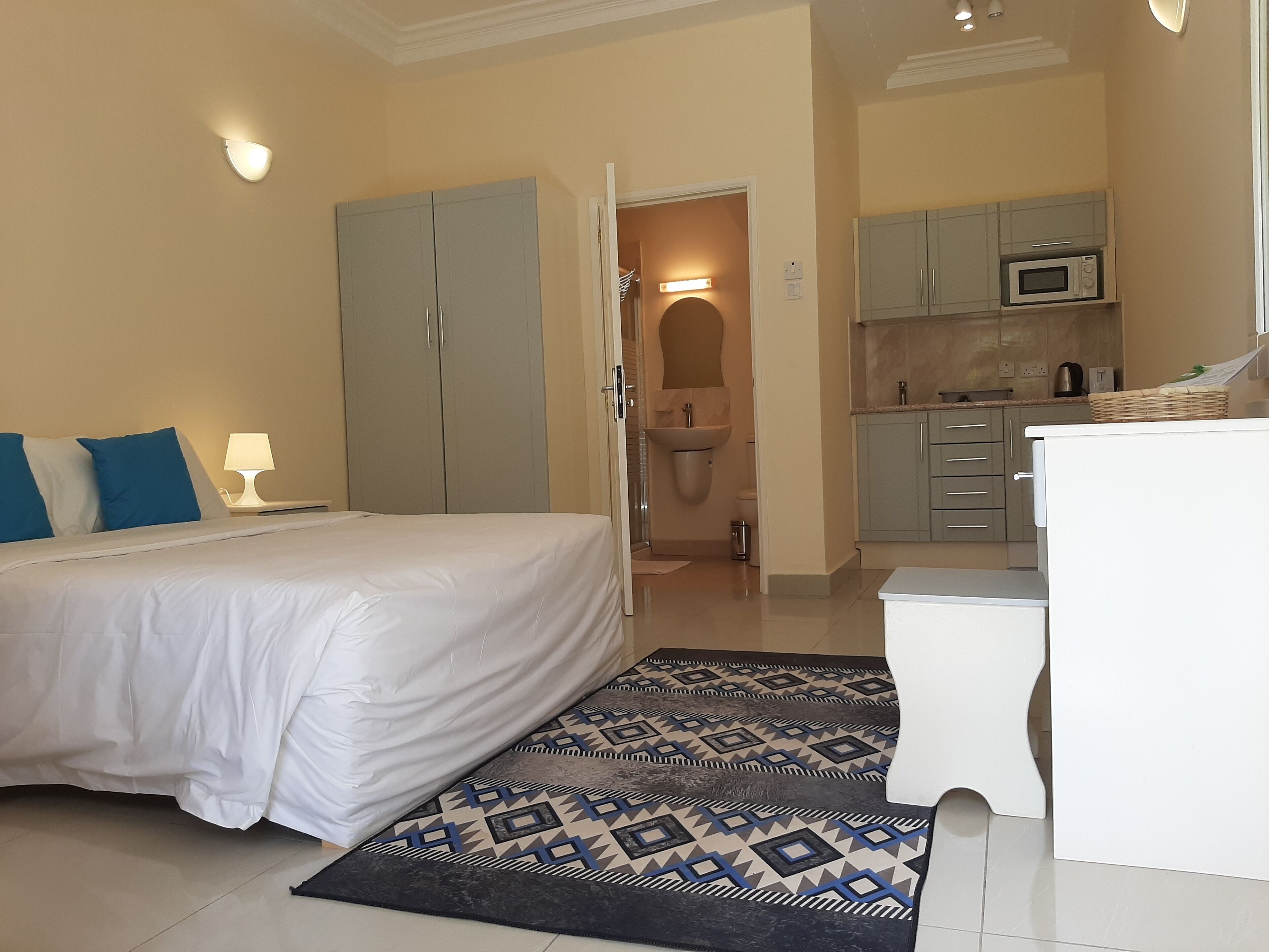 Habitación de hotel con cama, escritorio, kitchenette y baño.