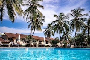 Una piscina con sillones de descanso y palmeras.
