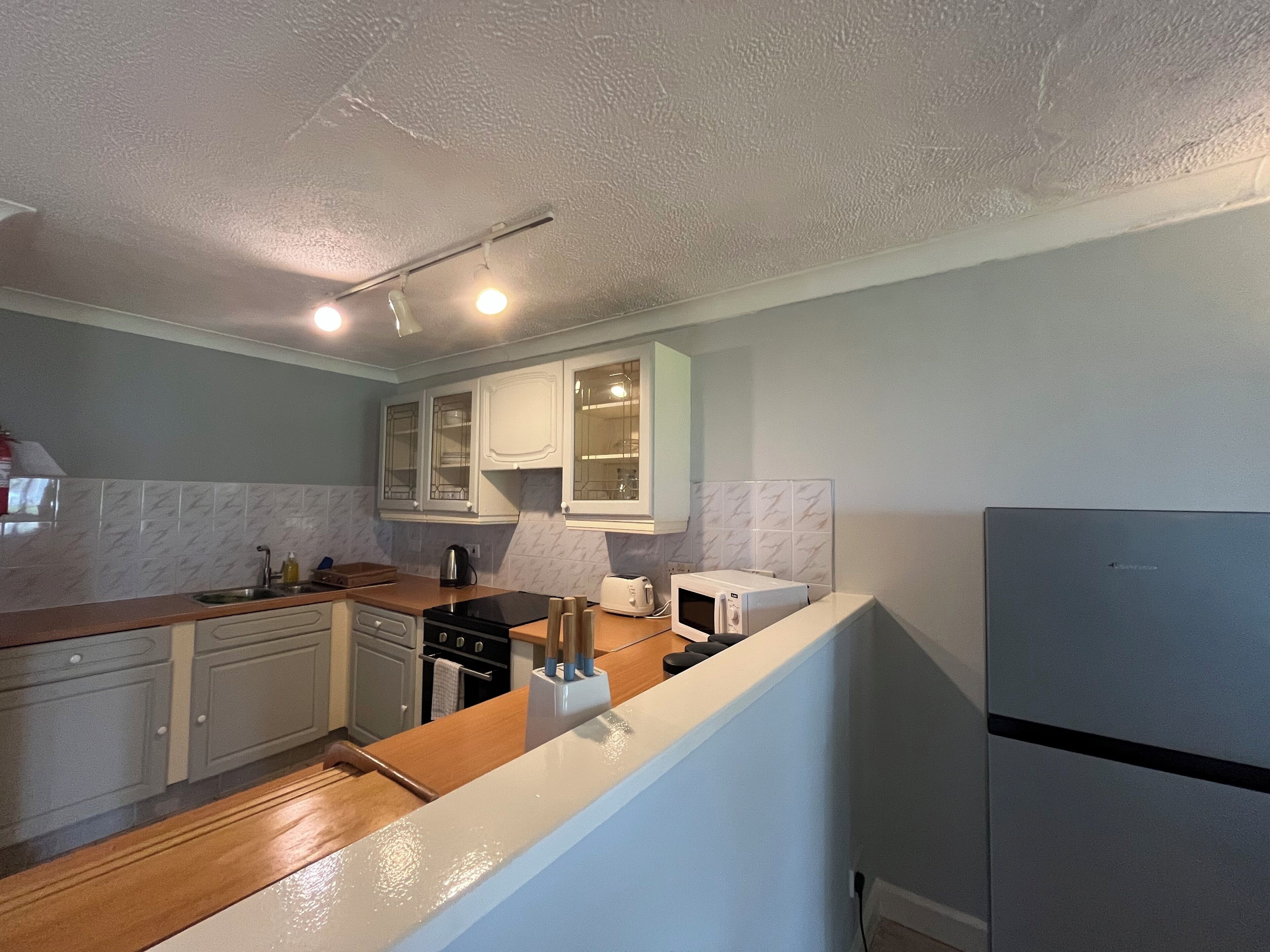 A kitchen with white cabinets, a stove, a sink, and a refrigerator.