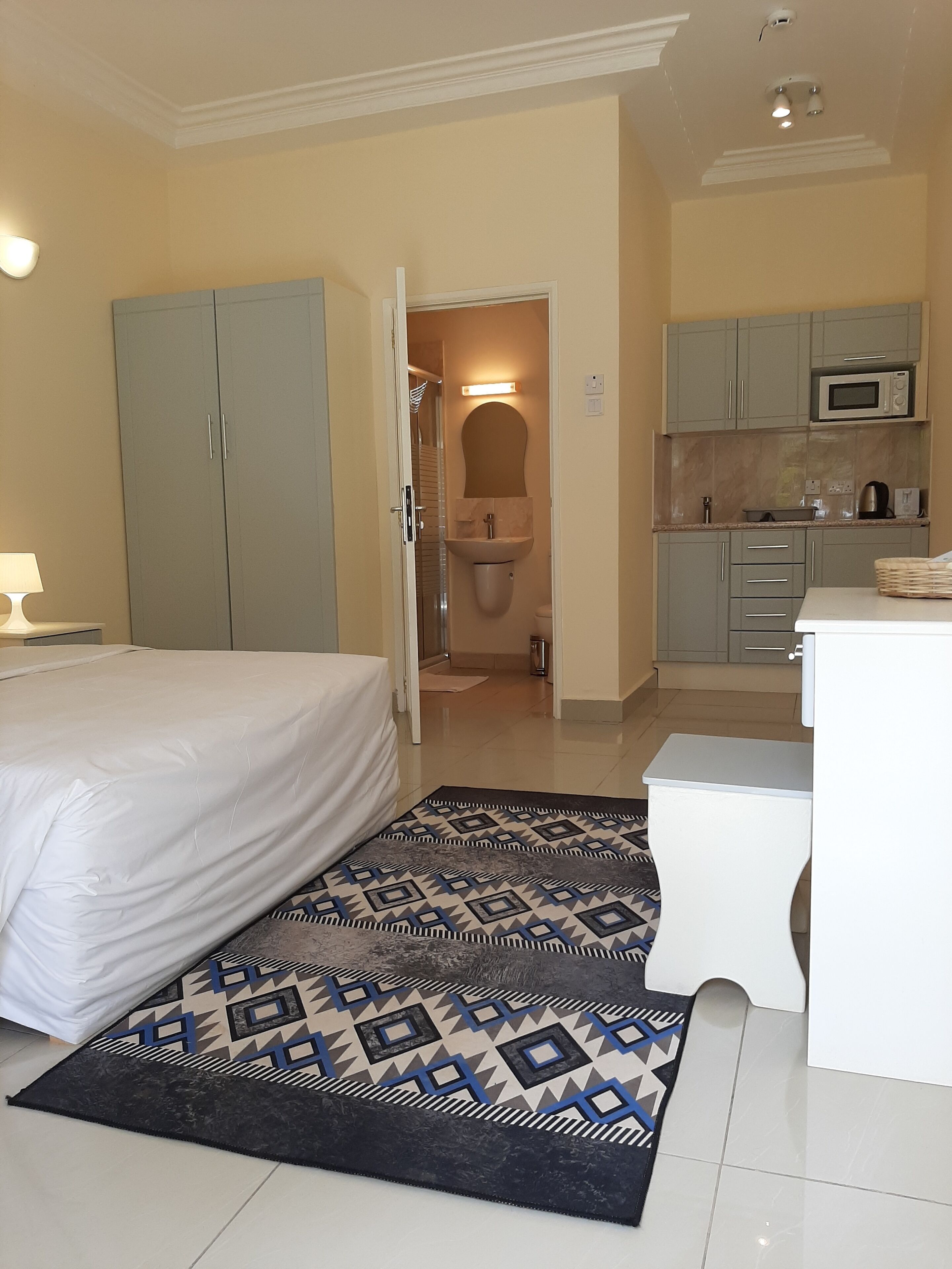 Habitación de hotel con cama, baño y kitchenette.