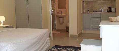 Habitación de hotel con cama, baño y kitchenette.