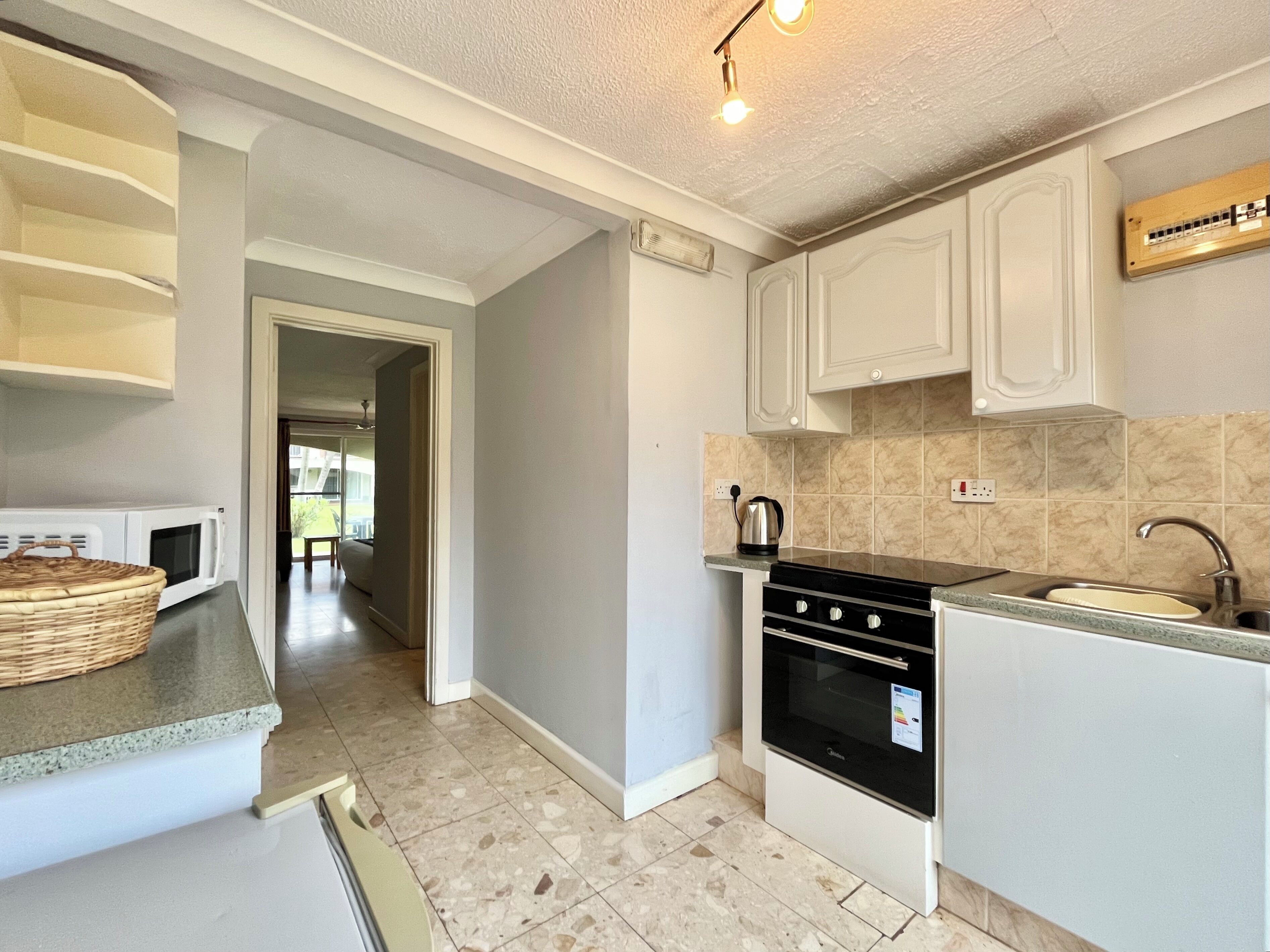 A kitchen with white cabinets, a stove, a microwave, and a sink.