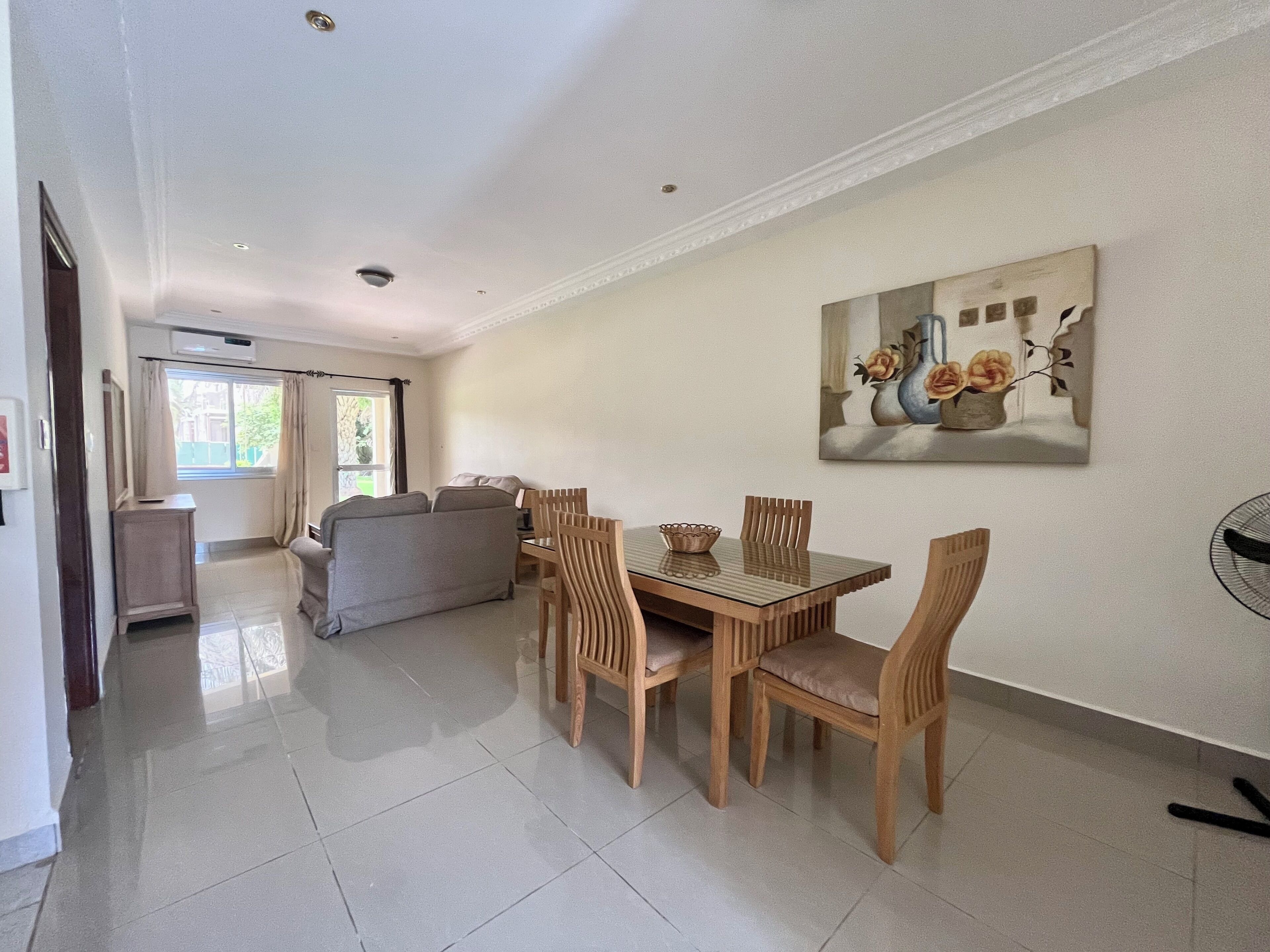 A dining area with a wooden table and chairs, a sofa, and a painting on the wall.