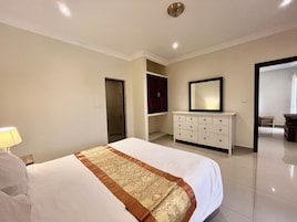 Una habitación de hotel con una cama grande, un aparador, un espejo y un vestidor.