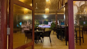 Un comedor interior con mesas y sillas, un techo con diseño tejido y lámparas colgantes.