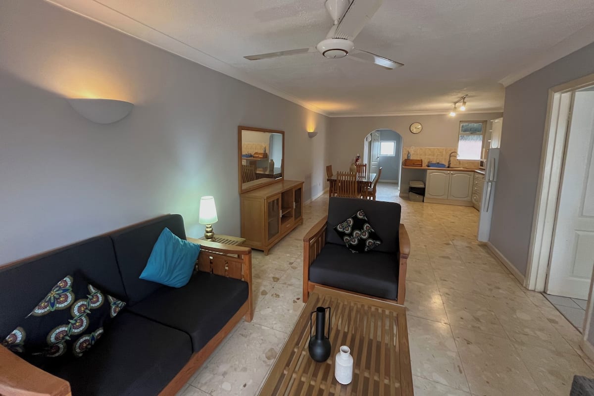 Ein Wohnzimmer mit Sofa, Sessel, Couchtisch und Deckenventilator.