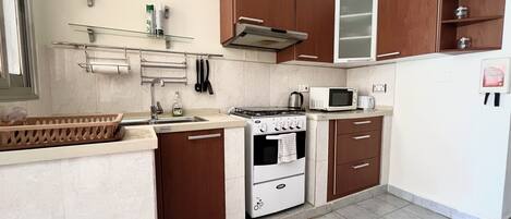 Una cocina compacta con estufa, microondas y armarios.