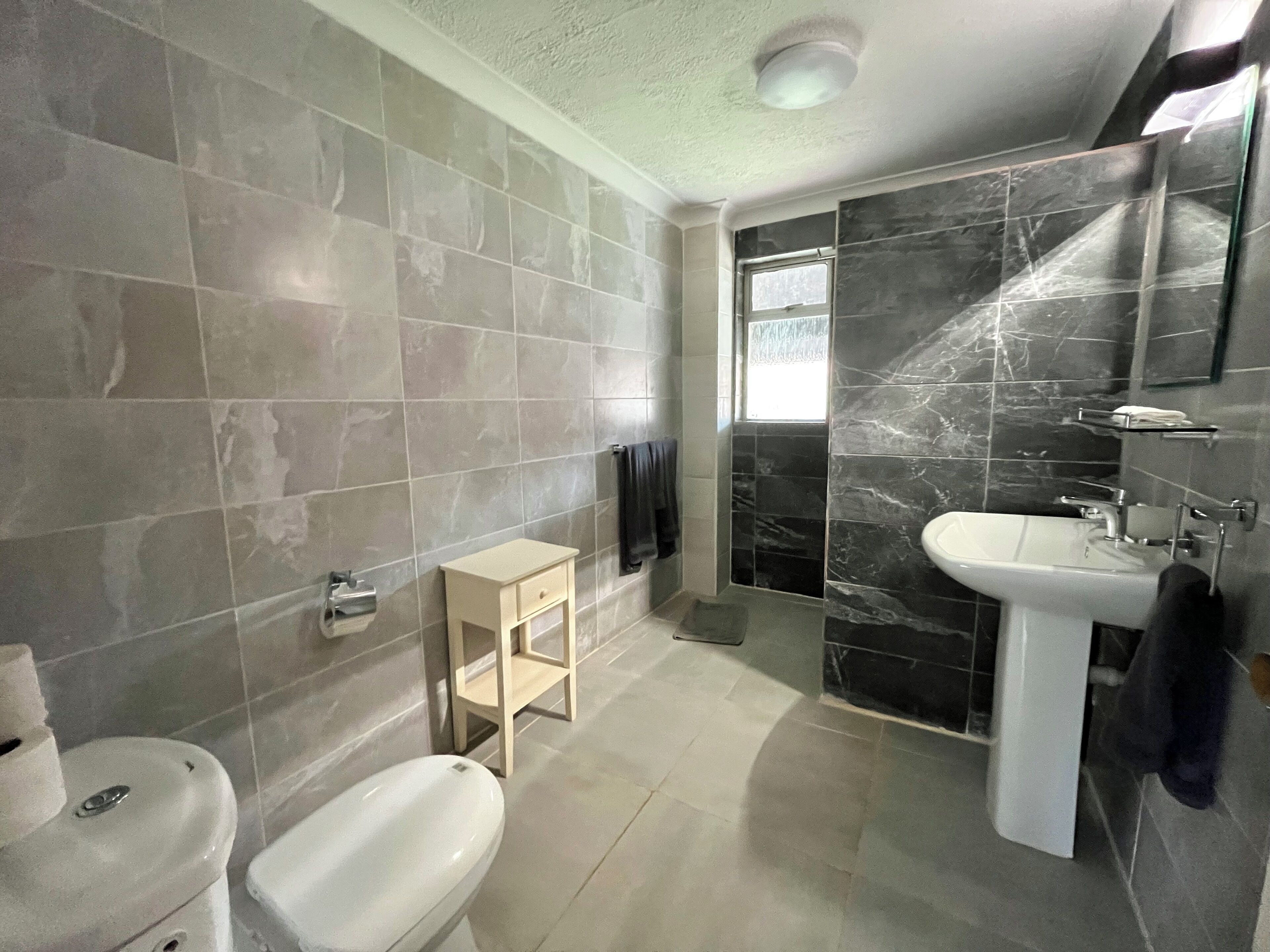 A bathroom with a toilet, a sink, and a shower area.