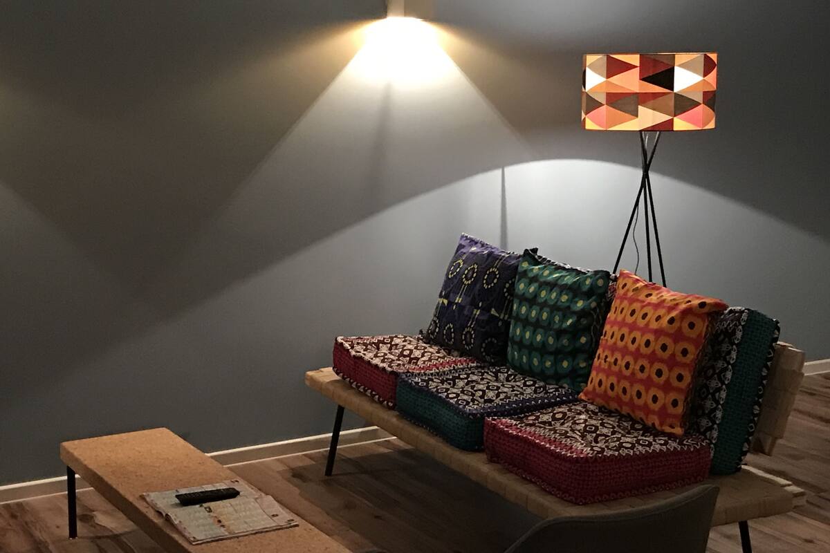 A modern living room with a sofa, cushions, a small table, and a floor lamp.