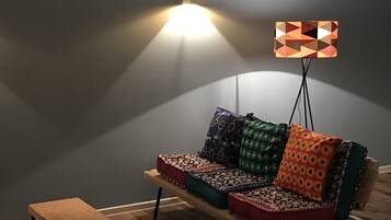 A modern living room with a sofa, cushions, a small table, and a floor lamp.