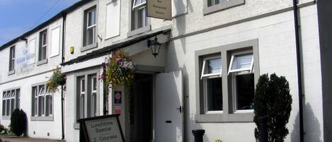 A white building with a signboard for 'The Craven Heifer Inn' indicating it is a bar, restaurant, and has rooms.