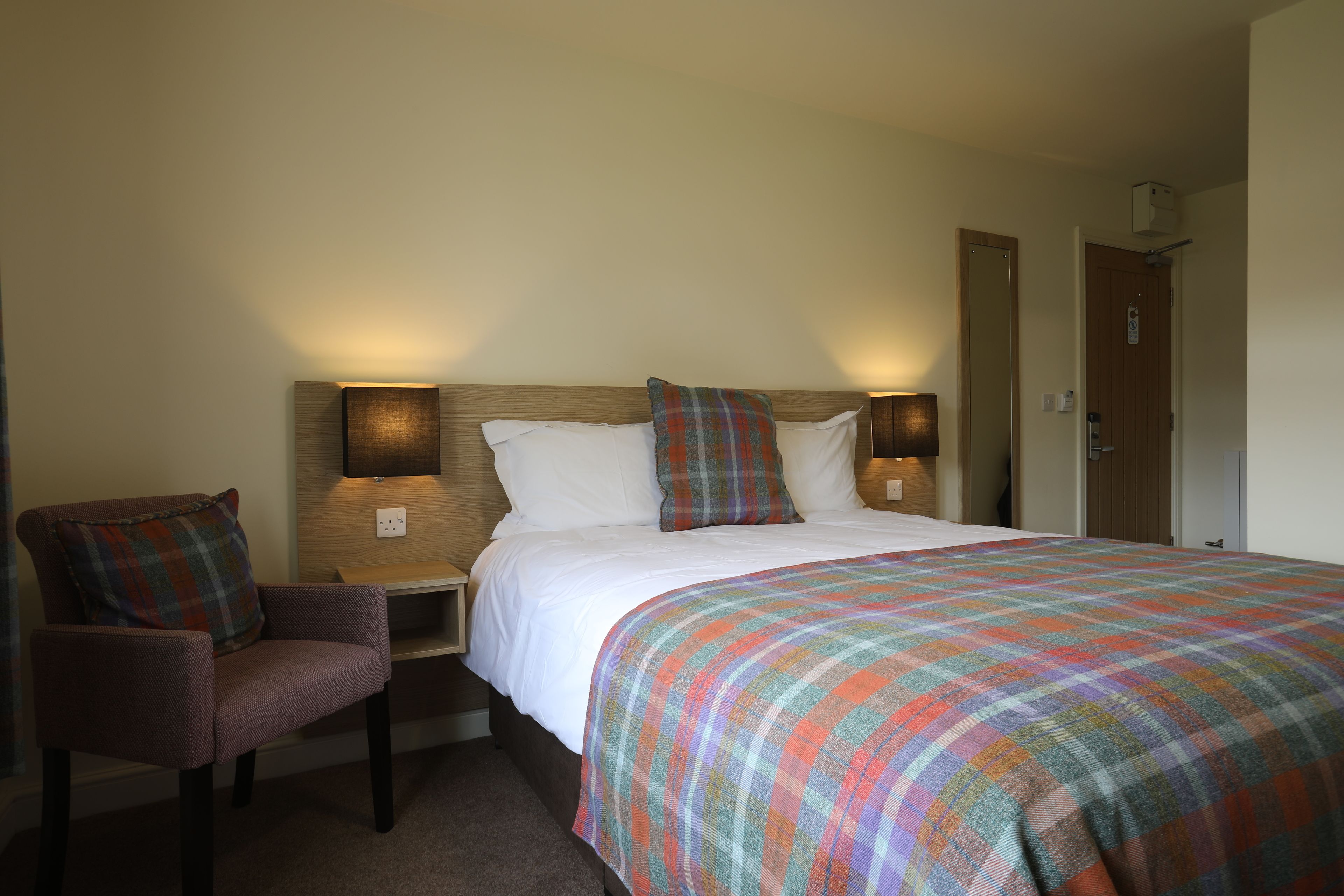 Une chambre d’hôtel avec un lit, une chaise et deux lampes de chevet.