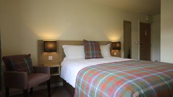 Une chambre d’hôtel avec un lit, une chaise et deux lampes de chevet.