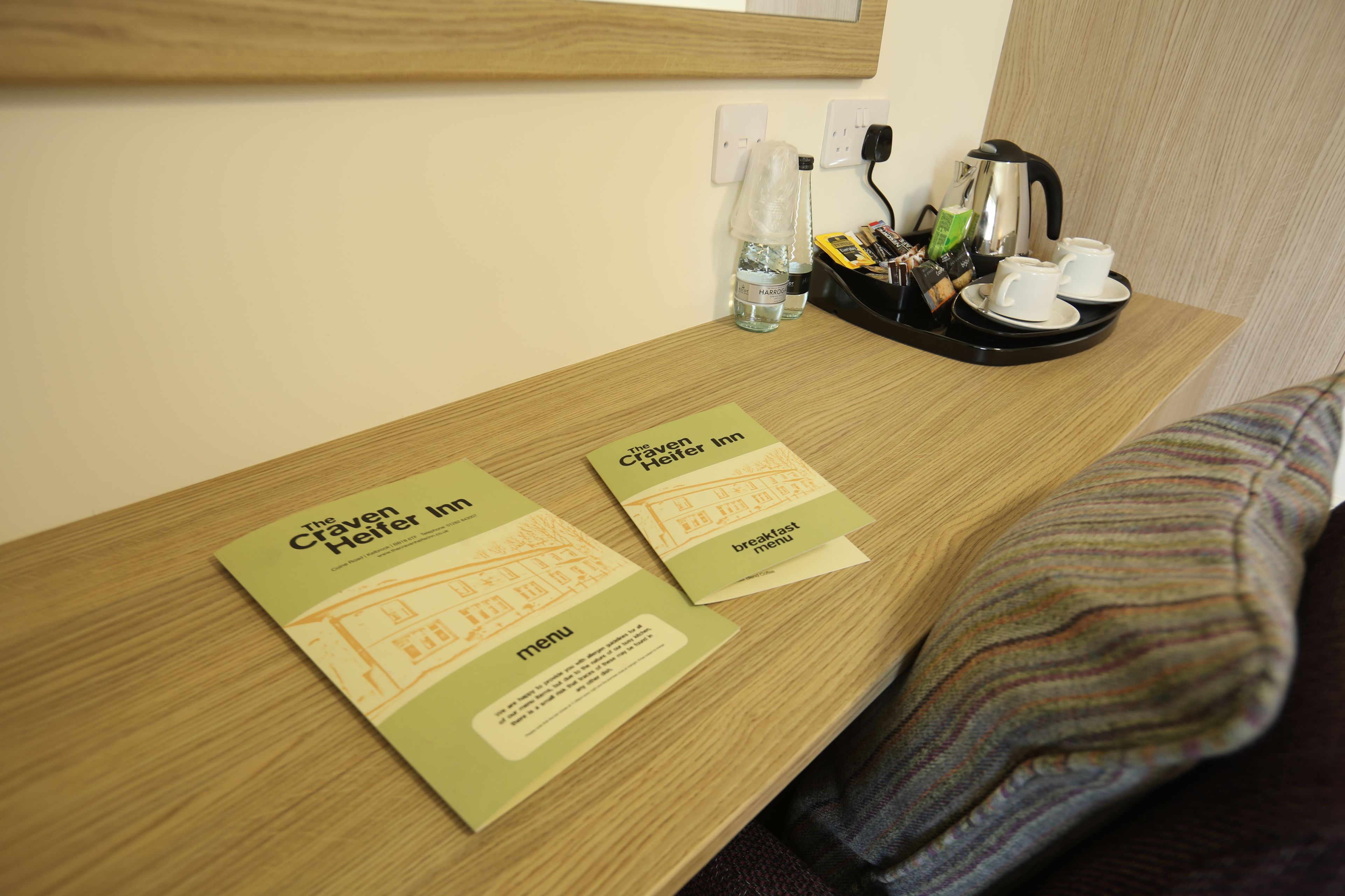 A hotel room with a wooden desk, a coffee maker, and two breakfast menus on the table.