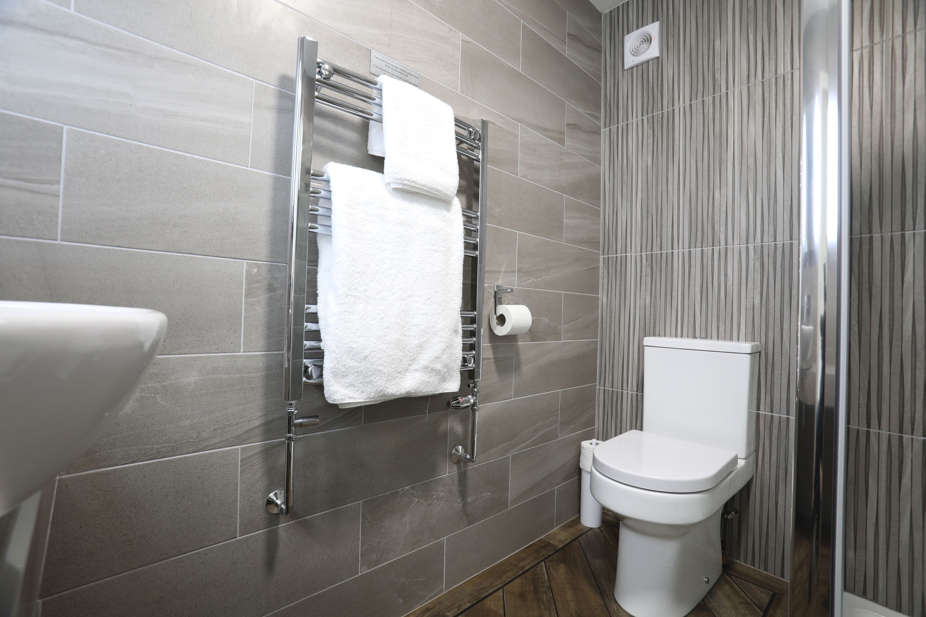 Une salle de bain moderne comprenant des toilettes, un porte-serviettes avec une serviette blanche et un espace douche.
