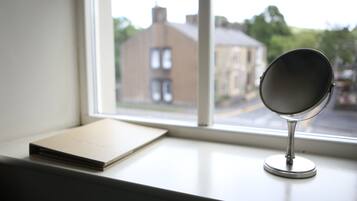 A mirror on a windowsill with a view of a building outside.