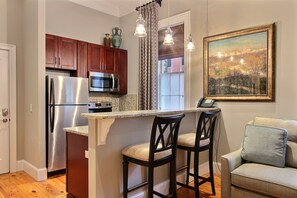 Una cocina con refrigerador, microondas y una isla con taburetes de bar.