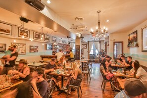 A restaurant with wooden floors, hanging lights, and a bar area. - The Suites at Bay (Savannah)