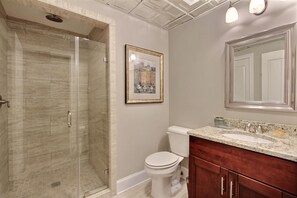 Un baño con ducha, inodoro, lavamanos y un cuadro en la pared.